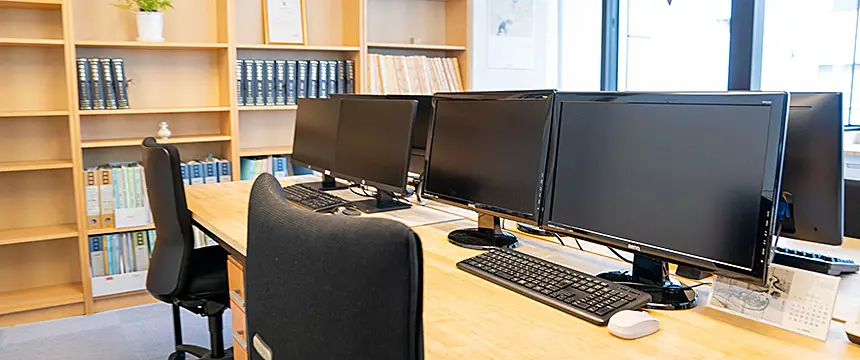 書棚とパソコンが並ぶオフィス風景